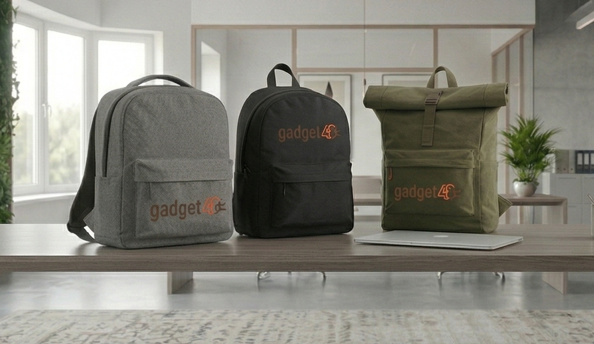 Tre modelli di zaini personalizzati con logo Gadget48 (grigio, nero e verde militare) esposti su una scrivania in un ufficio moderno e luminoso.
