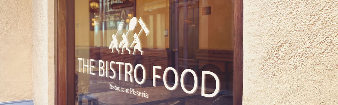 Titolare ristorante che in primo piano tiene un cartello con scritto marketing e sullo sfondo dei clienti seduti nel locale