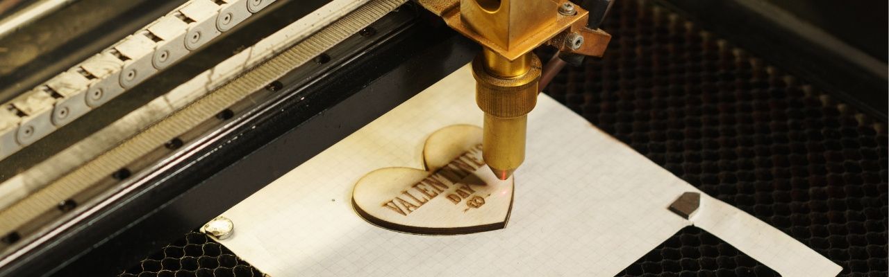 Macchina per le incisioni laser che incide una scritta su un cuore di legno