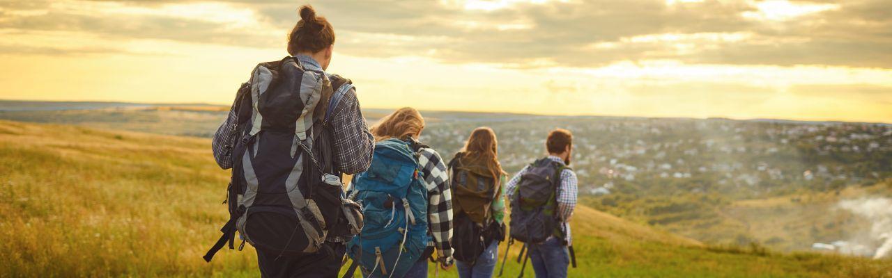 4 escursionisti o turisti con zaini, passeggiate in montagna al tramonto